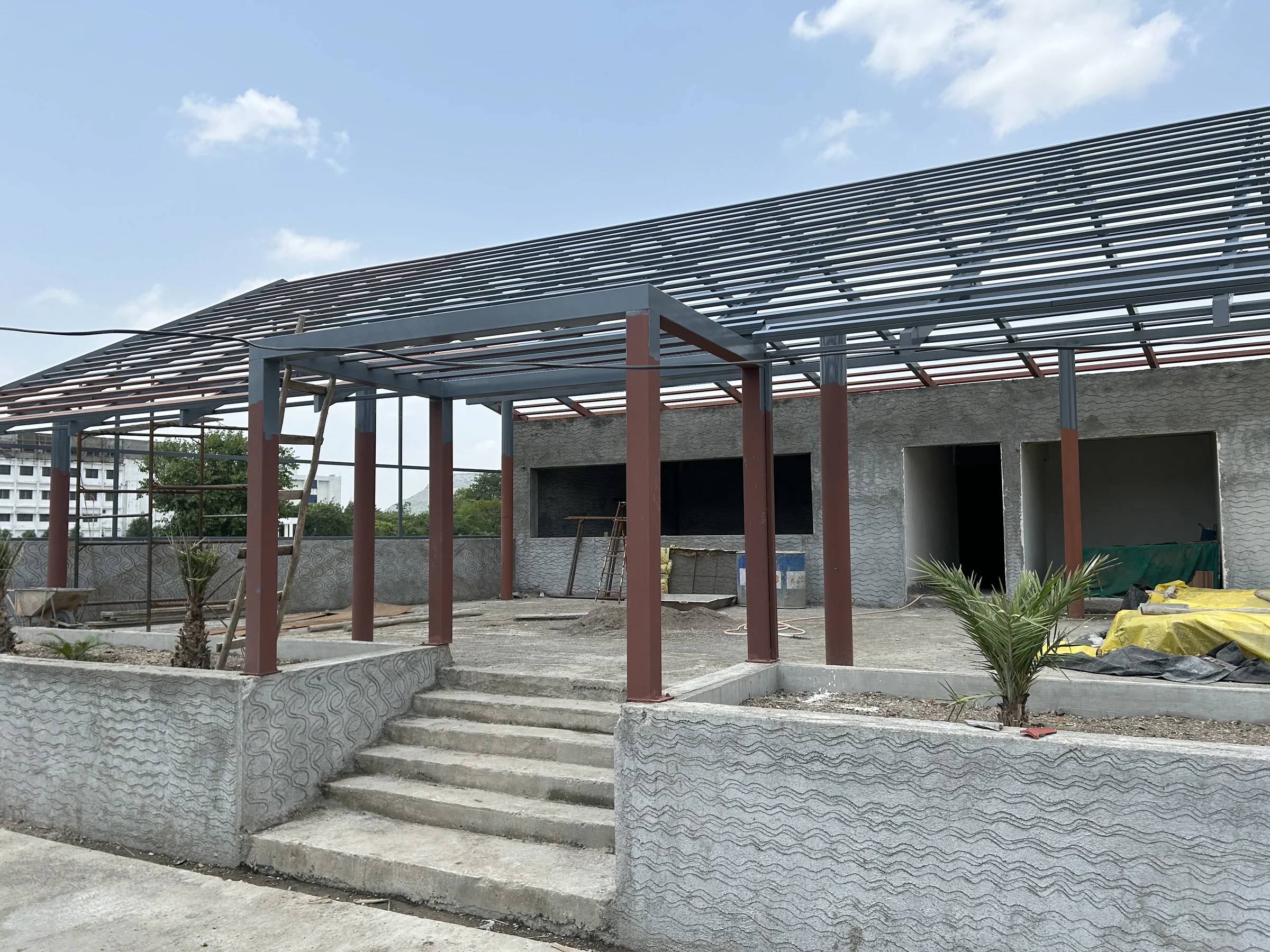 Site photograph: steel columns and roof purlins over a raised concrete plinth with steps